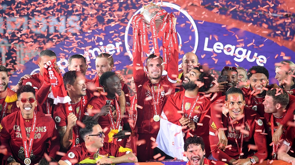 Liverpool players and staff lift the Premier League trophy.