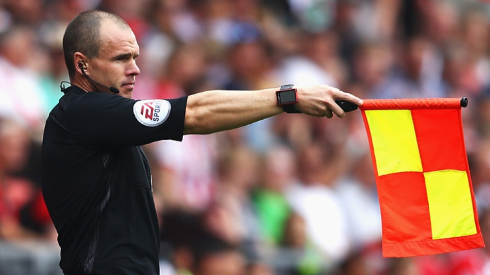 An assistant referee with his flag up.