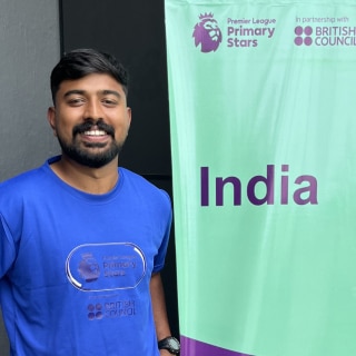 Sheheen Usman poses next to a Premier Skills banner in India