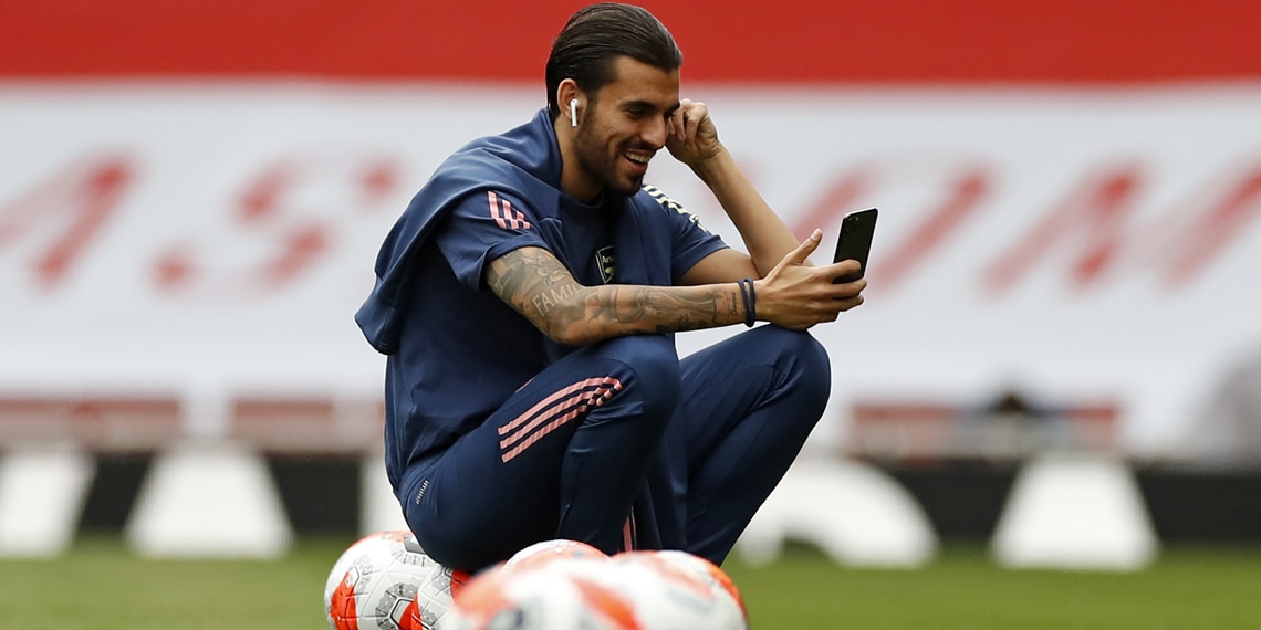 Dani Ceballos smiles as he checks his phone on the pitch