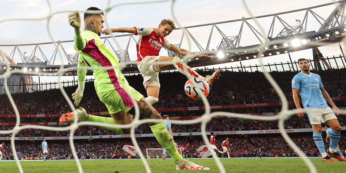 Manchester City's goalkeeper Ederson clears under pressure from Arsenal's midfielder Martin Odegaard