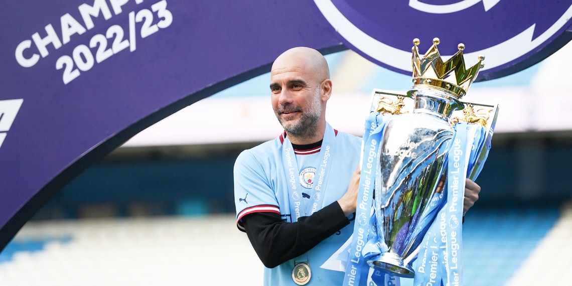 Pep Guardiola poses for a photograph with the Premier League Trophy