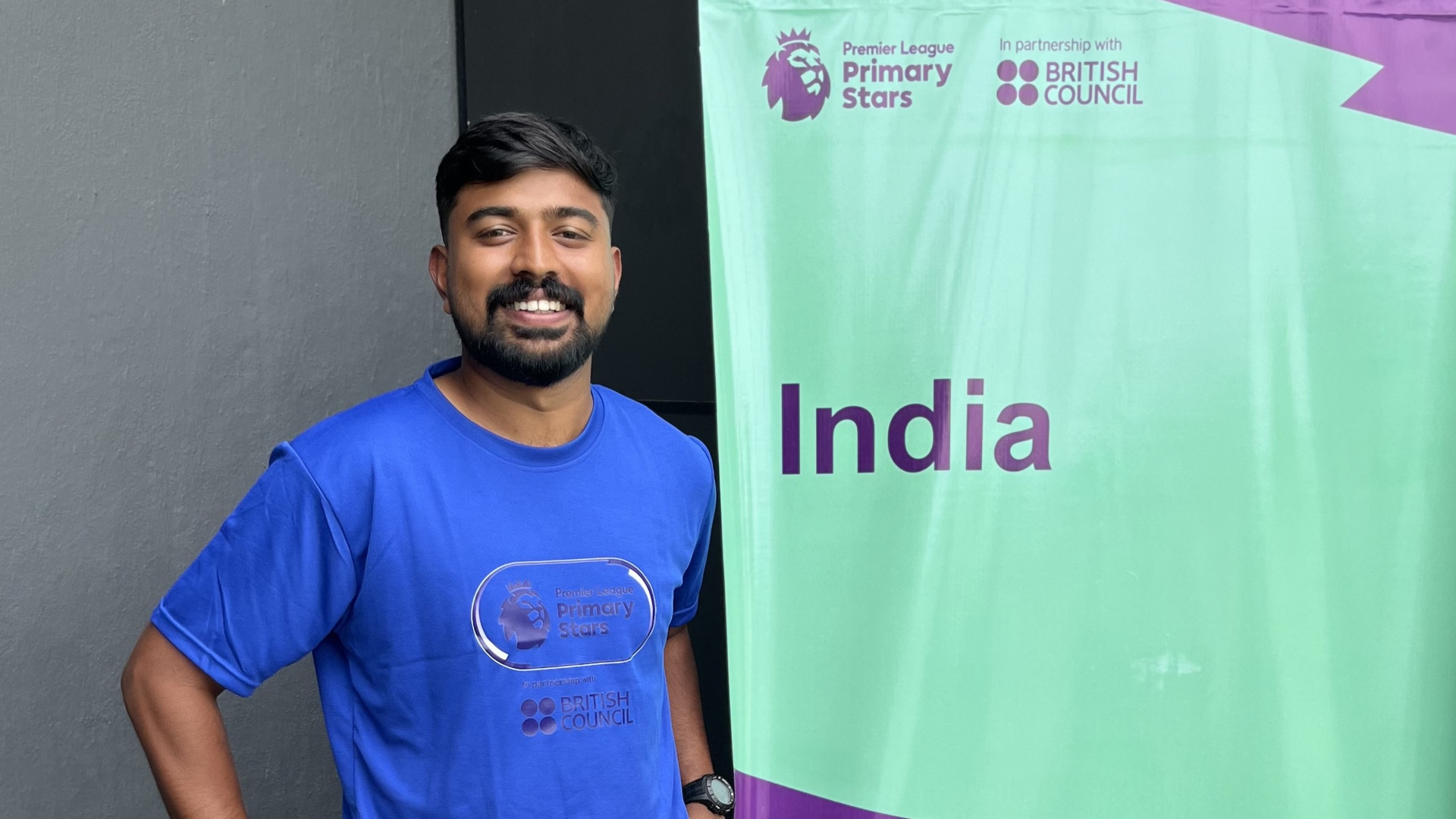 Sheheen Usman poses next to a Premier Skills banner in India