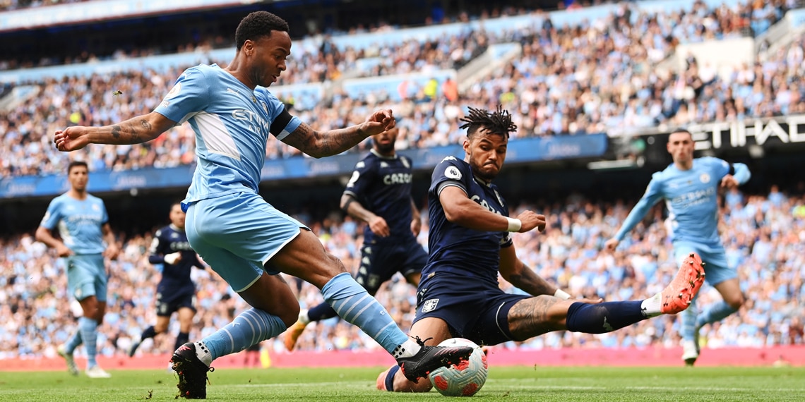 Manchester City player Raheem Sterling crosses the ball despite the attentions of Tyrone Mings of Aston Villa